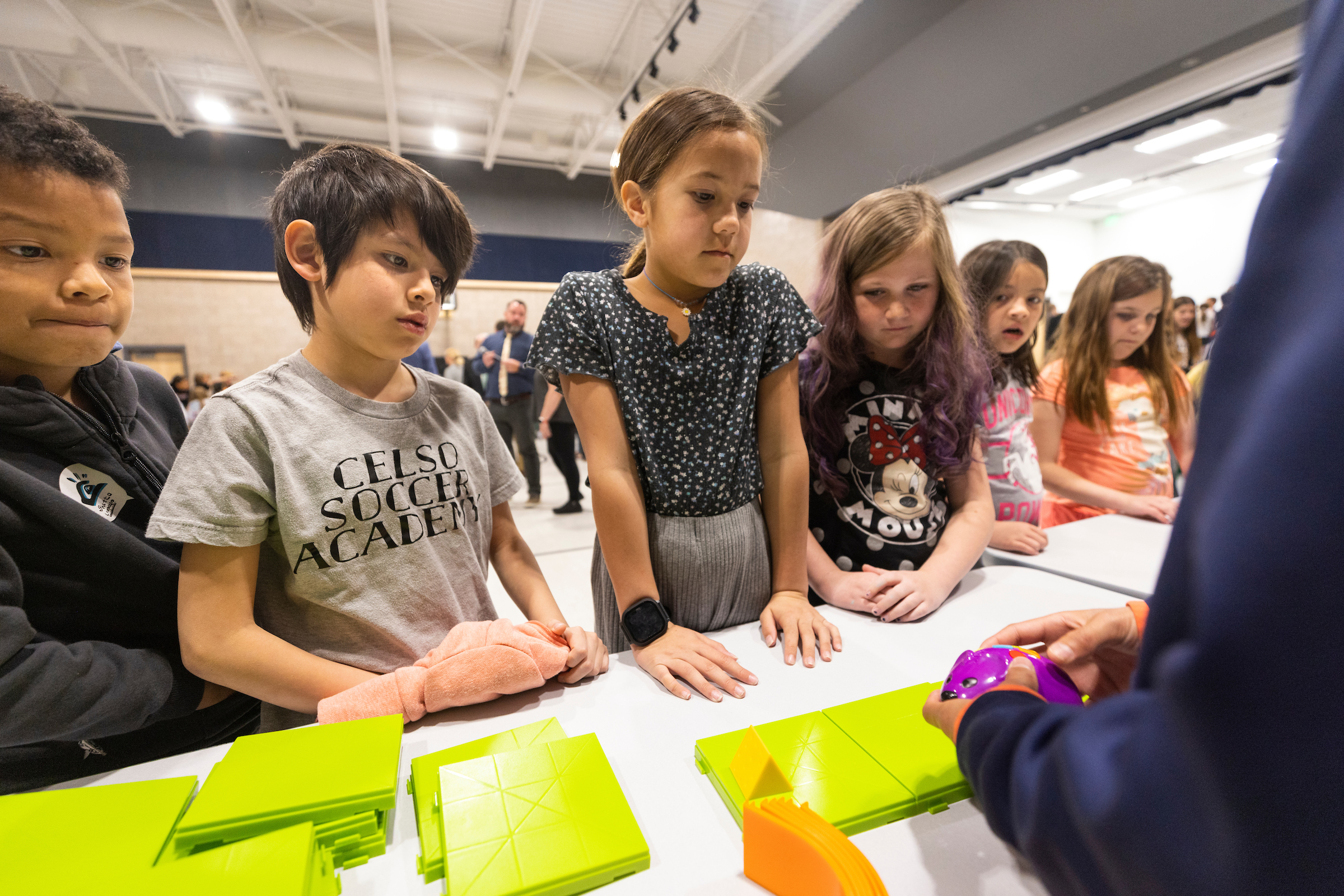 Unos niños observan una demostración de pequeños robots en un aula